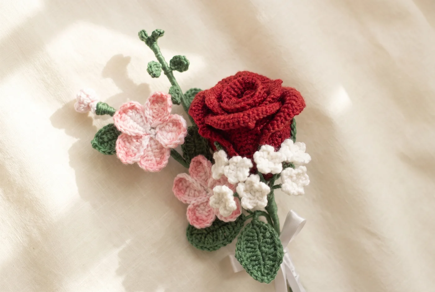 The crocheted bouquet arranged diagonally on ivory linen